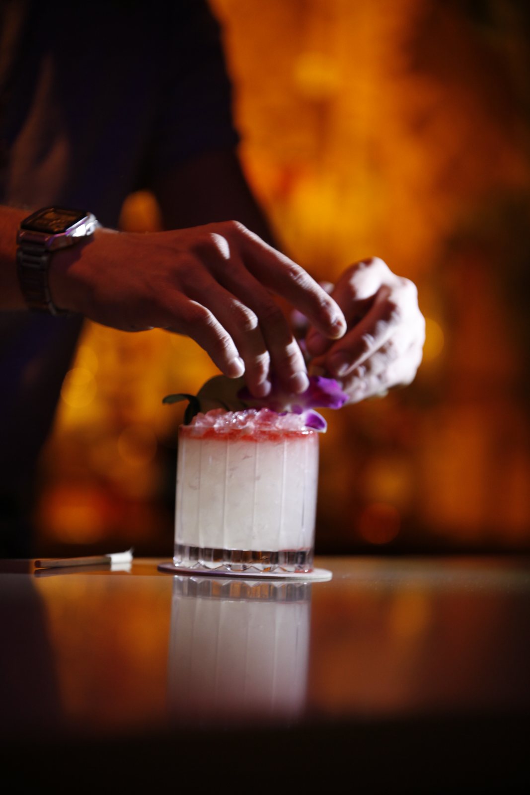 Garnishing a cocktail with an orchid behind the bar